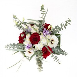As a seasoned florist serving South Croydon, I view this bouquet as a tribute to well-balanced artistry and quiet vibrance. The arrangement, illuminated by clear daylight reminiscent of a spring afternoon in Croham Hurst, centers on velvety red roses whose lush spirals evoke enduring affection and heartfelt intentions. Wide white gerberas surround them, their petals creamy against deep brown centers, acting as a foundation for the piece's visual rhythm. Adding a modern, whimsical twist, sprigs of pale lavender and soft purple lisianthus are interspersed, their buds suggesting stories yet to unfold-much like a morning walk near Coombe Woods. The bouquet's base is encircled by structured, glossy dark green leaves, their sheen highlighting the ensemble's freshness and fullness. Overarching tendrils of eucalyptus, with their silvery discs and aromatic lift, bring gentle motion and a whisper of wildness that's familiar to anyone living near South Croydon's open spaces. Through the clear glass vase, glistening stems rest in water, reflecting commitment to quality and attention to detail that characterizes local floral delivery. This bouquet, with its subtle blend of fragrance and texture, is an inviting presence for new beginnings, celebrations, or gentle remembrance-a living testament to the thoughtfulness of professional South Croydon florists.